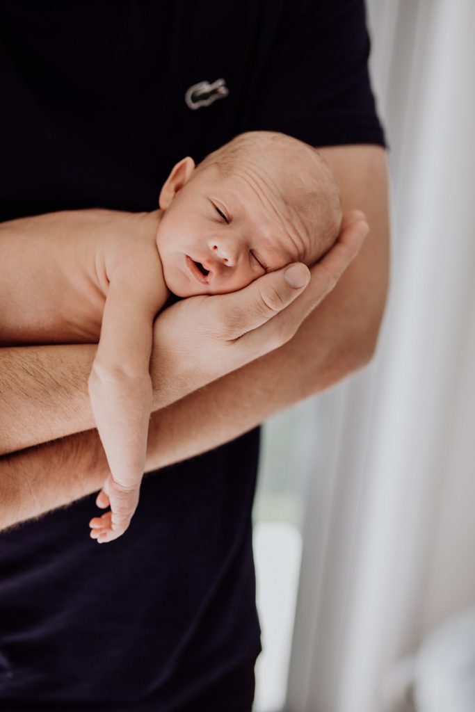 Life - Newborn - A man in a black shirt holds a newborn baby in his arms, with his head resting in his hand